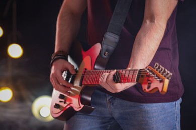 Photo of Man playing electric guitar on stage, closeup. Rock concert