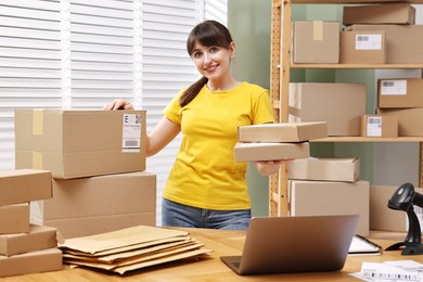 Photo of Parcel packing. Post office worker with parcels at wooden table indoors