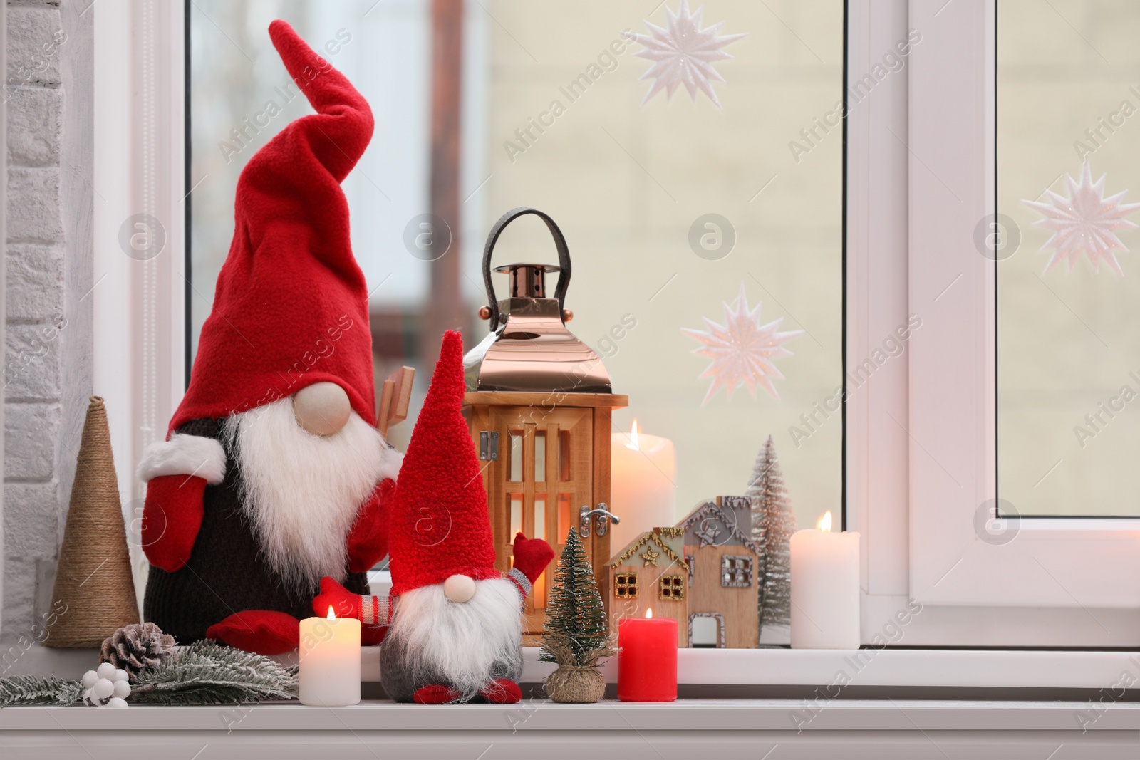 Photo of Cute Christmas gnomes and other festive decorations on windowsill in room, space for text