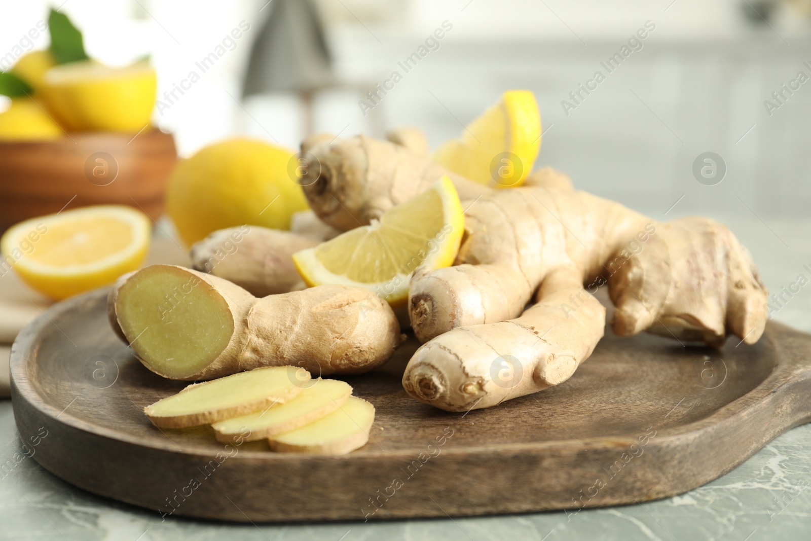 Photo of Fresh lemon and ginger on grey marble table indoors, closeup