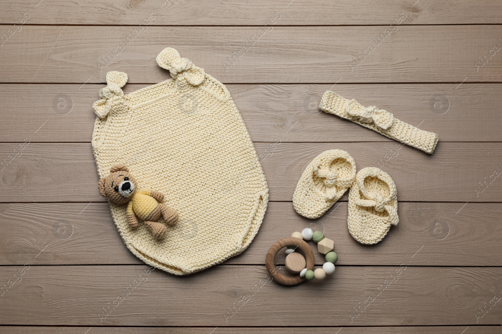 Photo of Flat lay composition with cute baby knitwear for photoshoot on wooden background