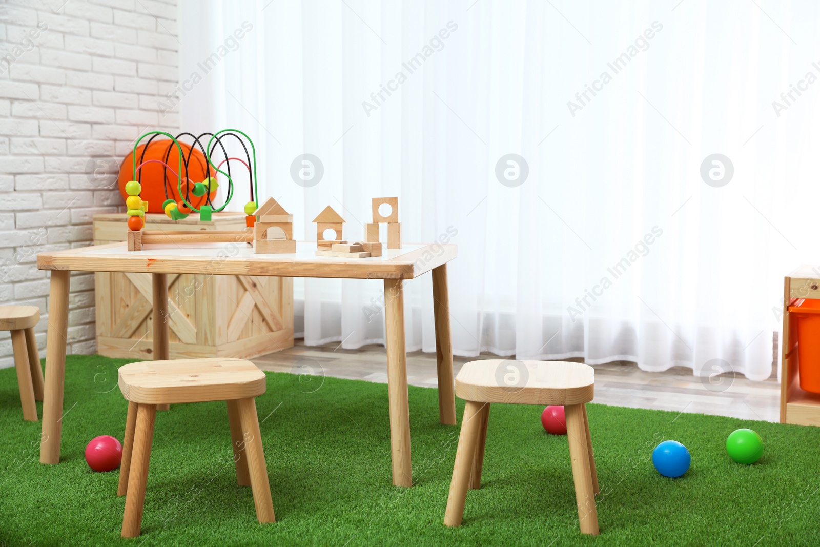 Photo of Stylish playroom interior with toys and modern wooden furniture. Space for design