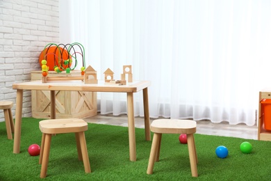 Stylish playroom interior with toys and modern wooden furniture. Space for design