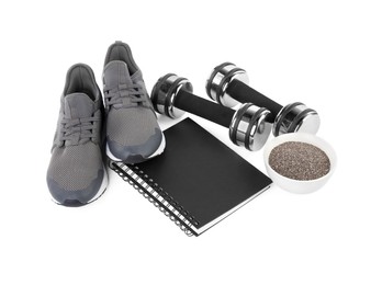 Photo of Weight loss concept. Composition with sneakers, dumbbells and notebook isolated on white