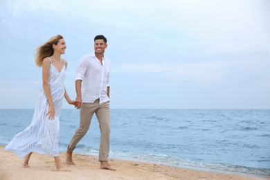 Happy couple having romantic walk on beach. Space for text