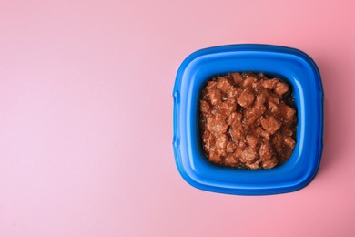 Wet pet food in feeding bowl on pink background, top view. Space for text