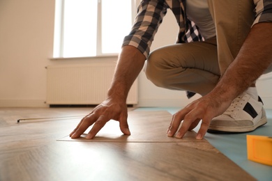 Professional worker installing new parquet flooring indoors, closeup