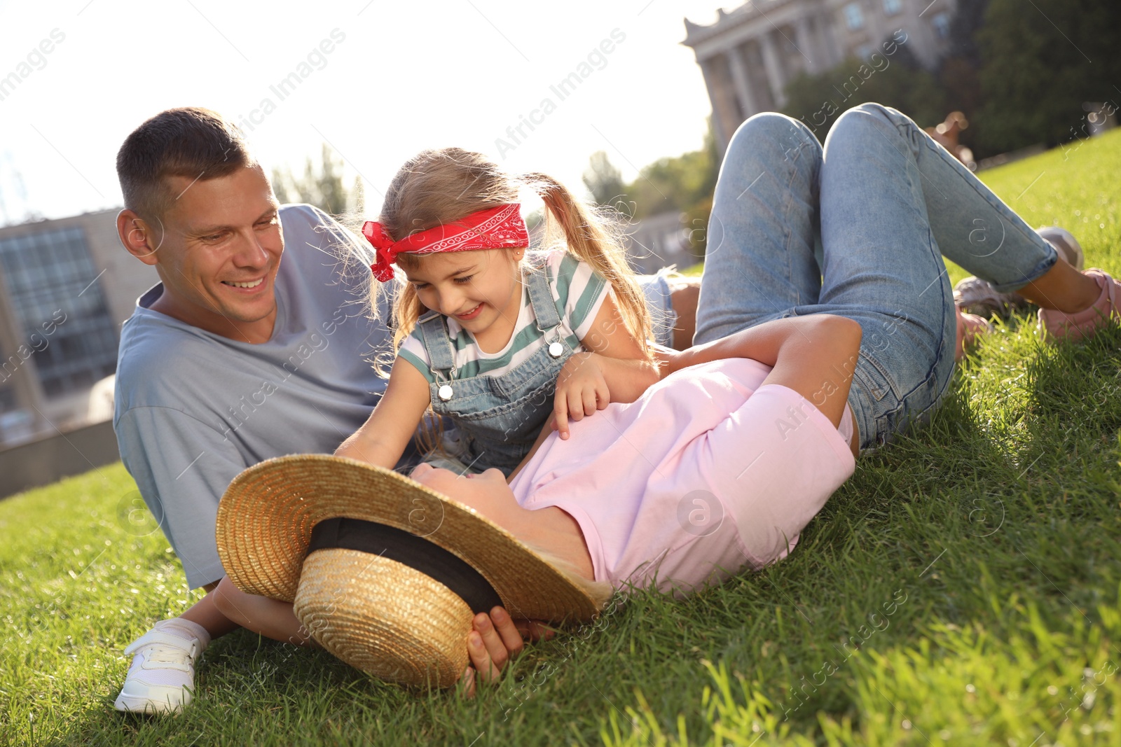 Photo of Happy parents with their child having fun on green grass. Spending time in nature