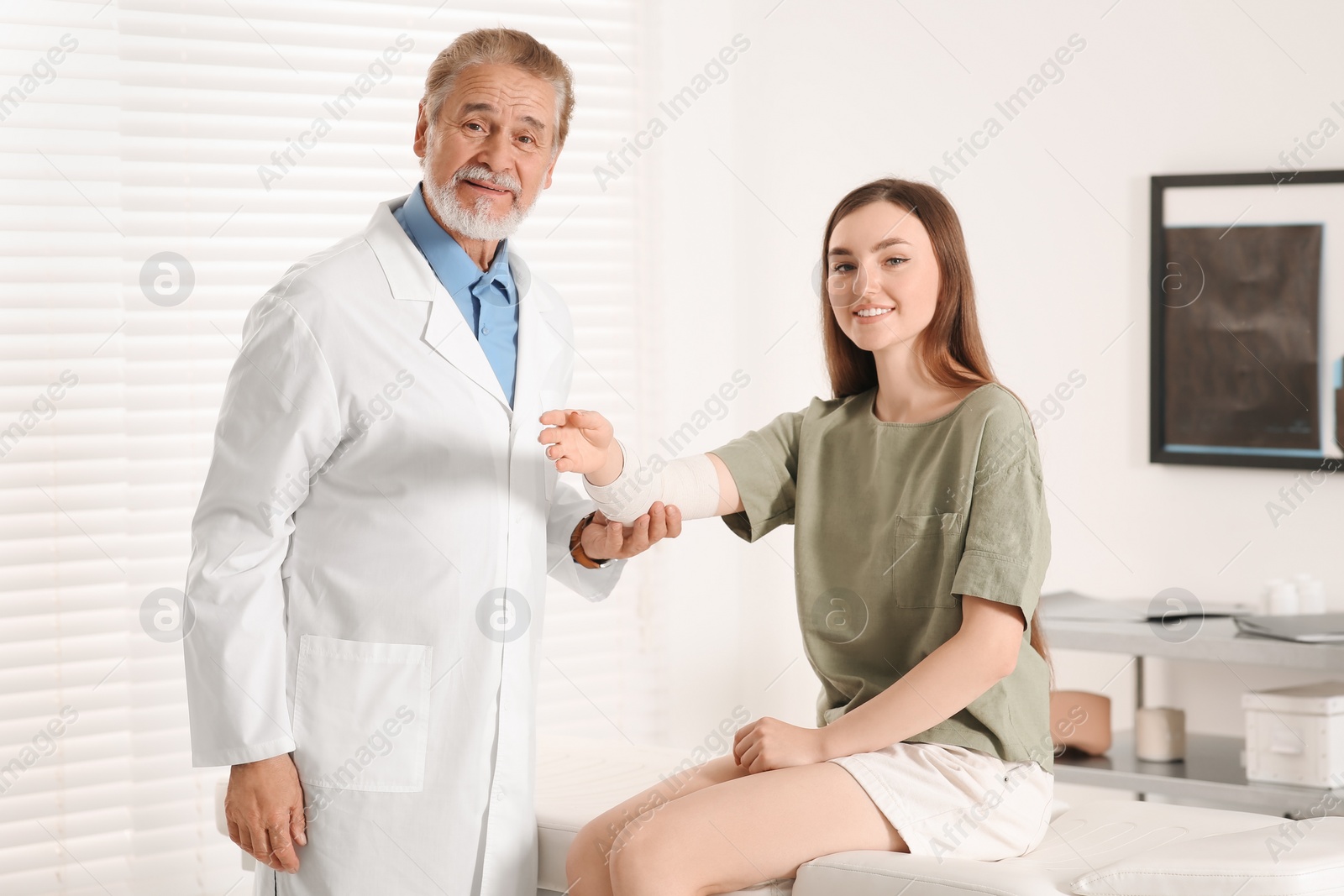 Photo of Orthopedist applying bandage onto patient's elbow in clinic
