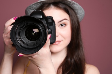 Female photographer with professional camera on color background