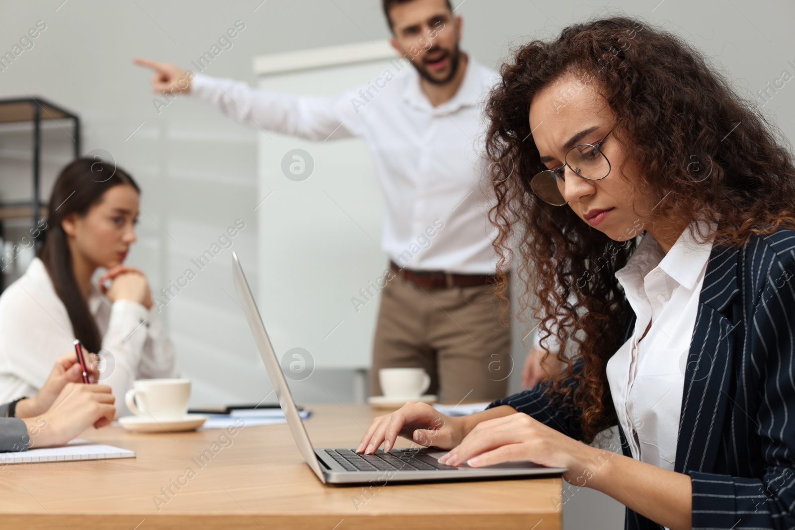 Photo of Man screaming at African American woman in office. Racism concept