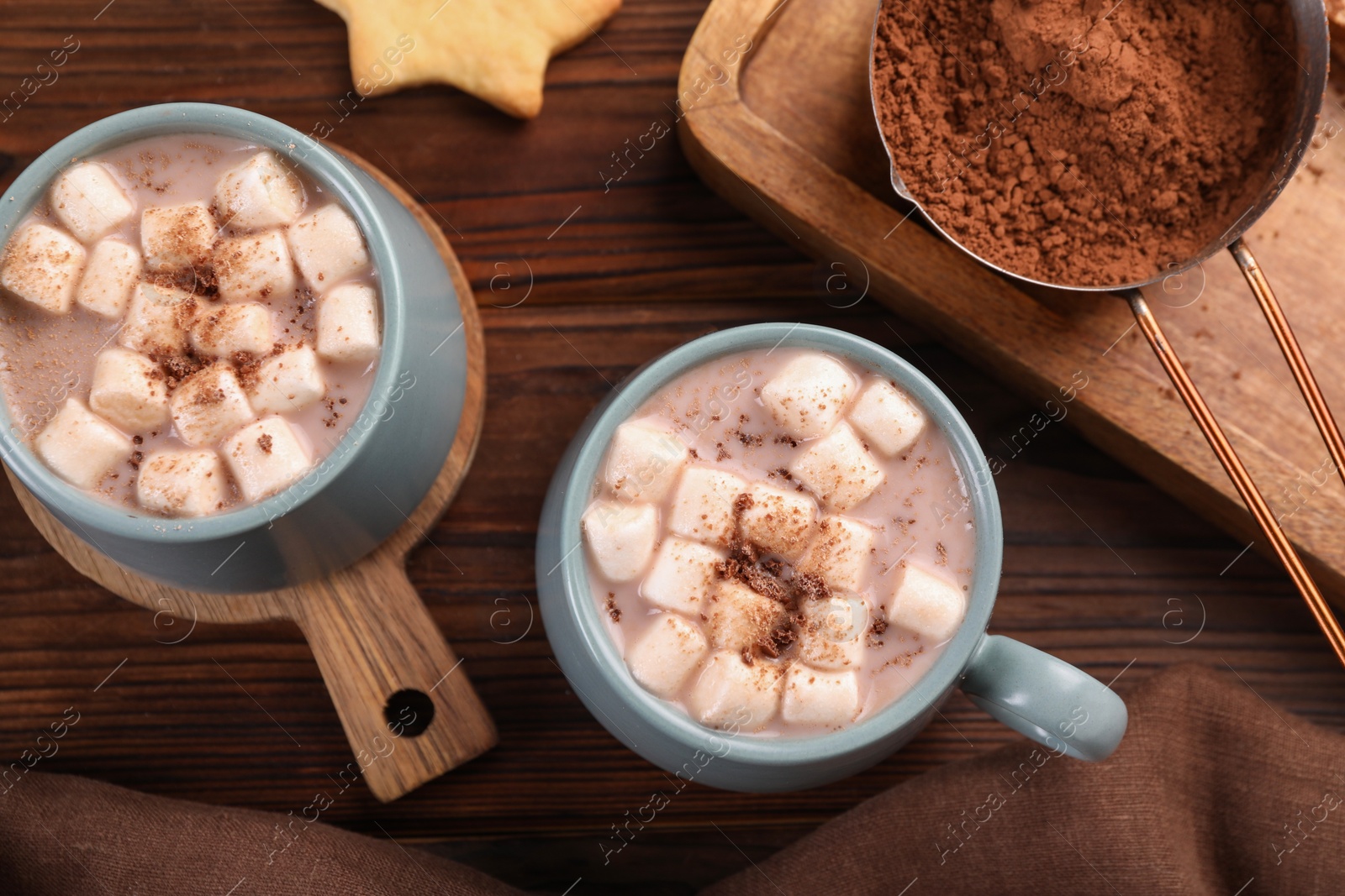 Photo of Cups of aromatic hot chocolate with marshmallows and cocoa powder on wooden table, flat lay