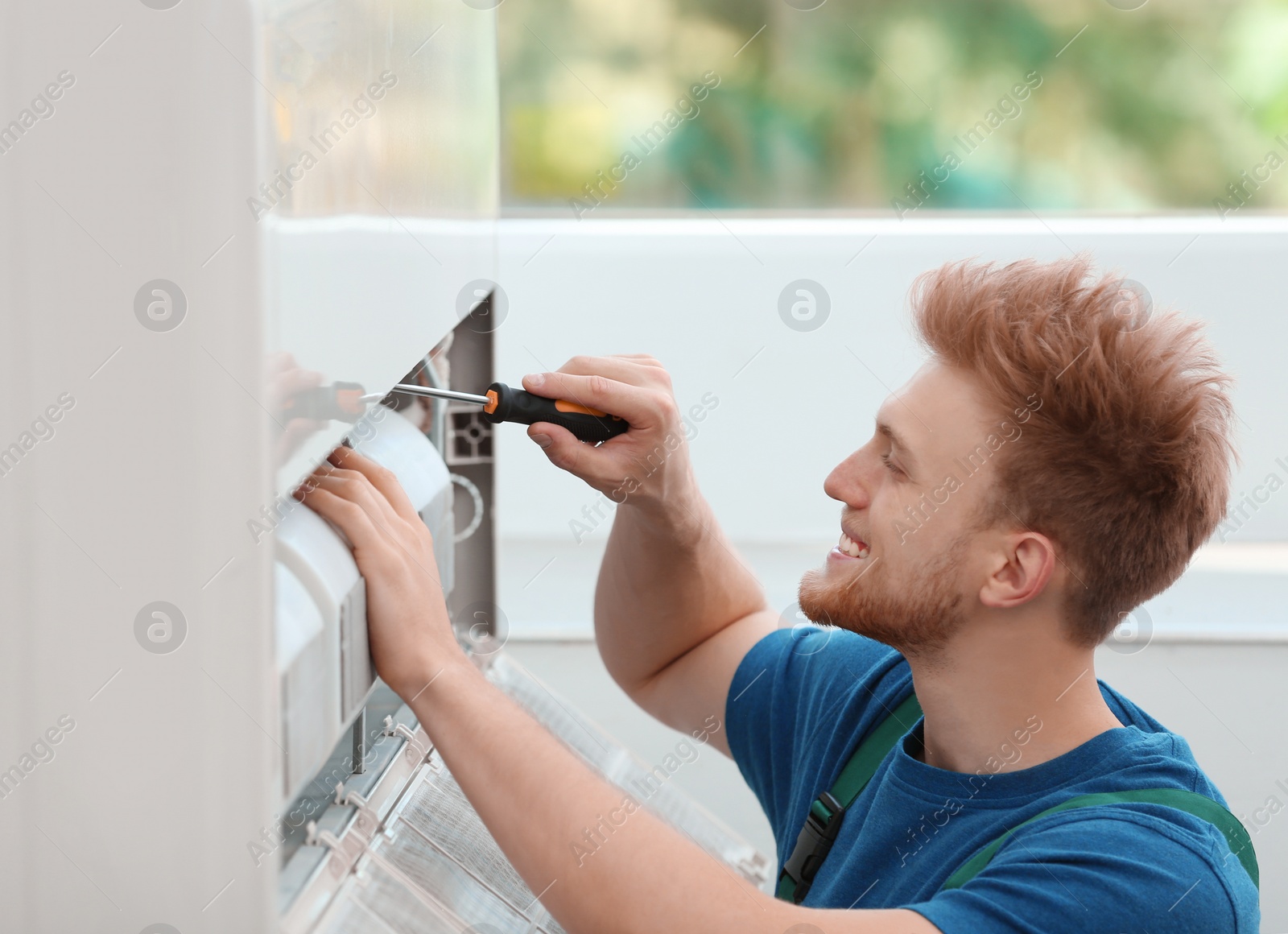 Photo of Professional technician maintaining modern air conditioner indoors