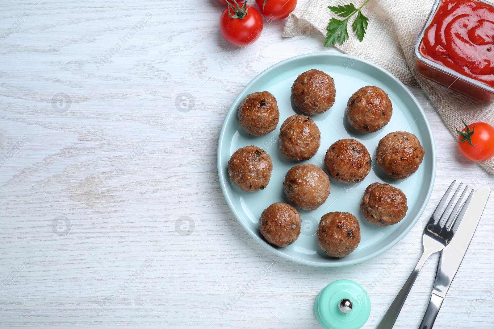 Photo of Tasty cooked meatballs served on white wooden table, flat lay. Space for text