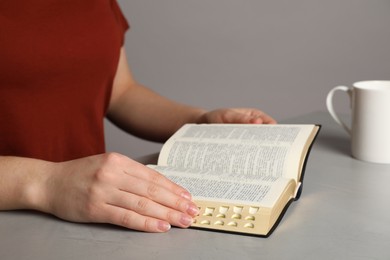 Photo of Woman reading Bible at light table, closeup