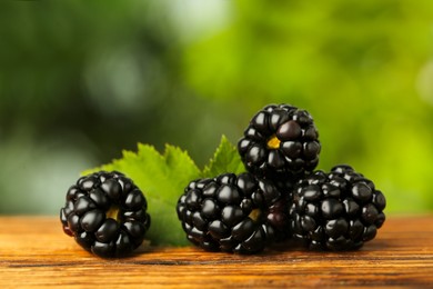 Photo of Fresh ripe blackberries on wooden table outdoors, closeup