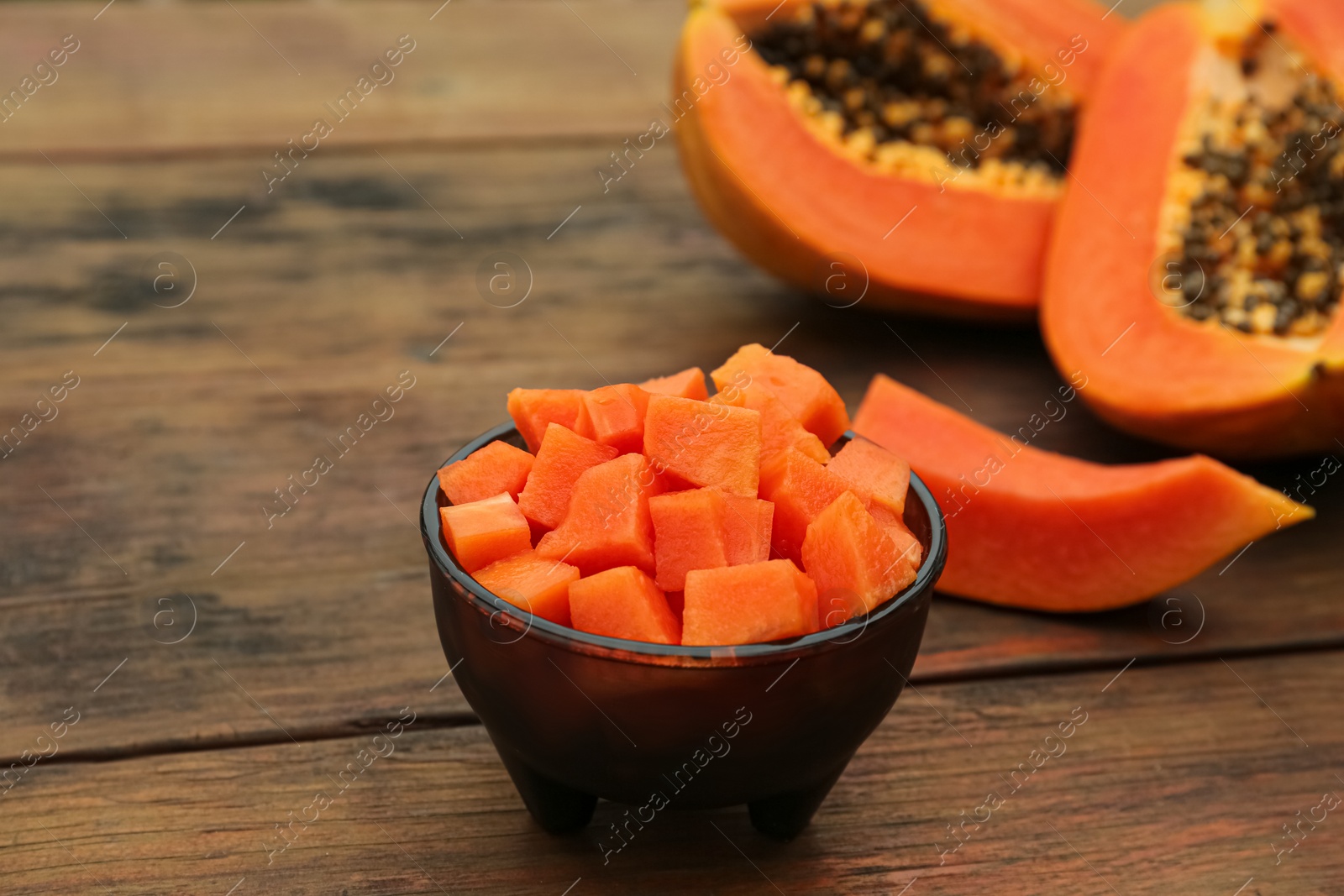 Photo of Tasty cut papaya fruits on wooden table, closeup