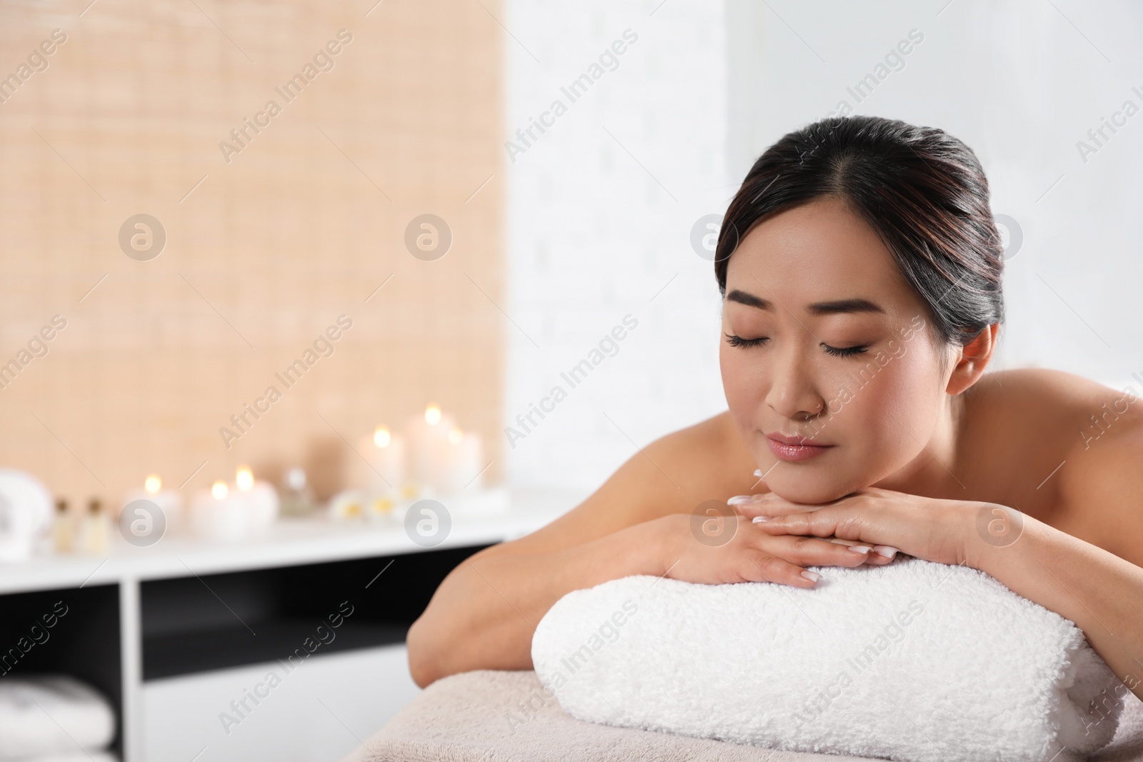 Photo of Beautiful Asian woman lying on massage table in spa salon. Space for text