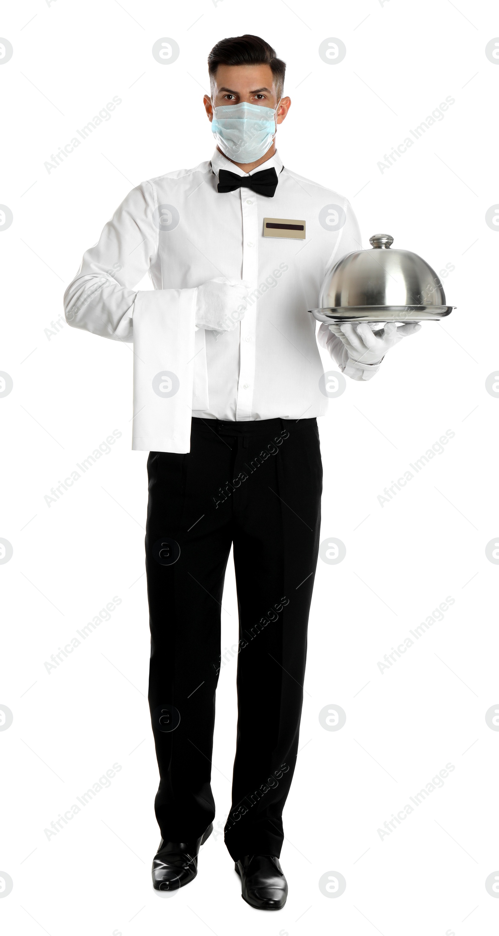 Photo of Waiter in medical face mask holding tray with lid on white background