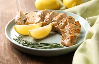 Photo of Tasty lemon chicken on wooden table, closeup