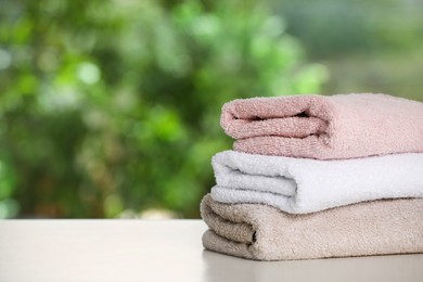 Stacked towels on white table against blurred background, space for text