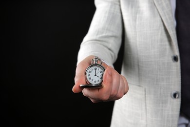 Photo of Closeup view of businessman holding pocket watch on black background, space for text. Time management