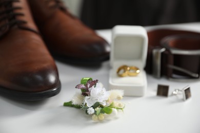 Photo of Wedding stuff. Composition with stylish boutonniere on white surface, closeup