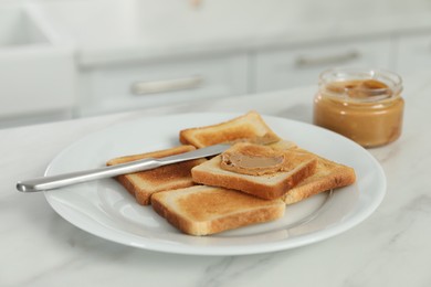 Photo of Tasty nut butter and toasts on white marble table, closeup