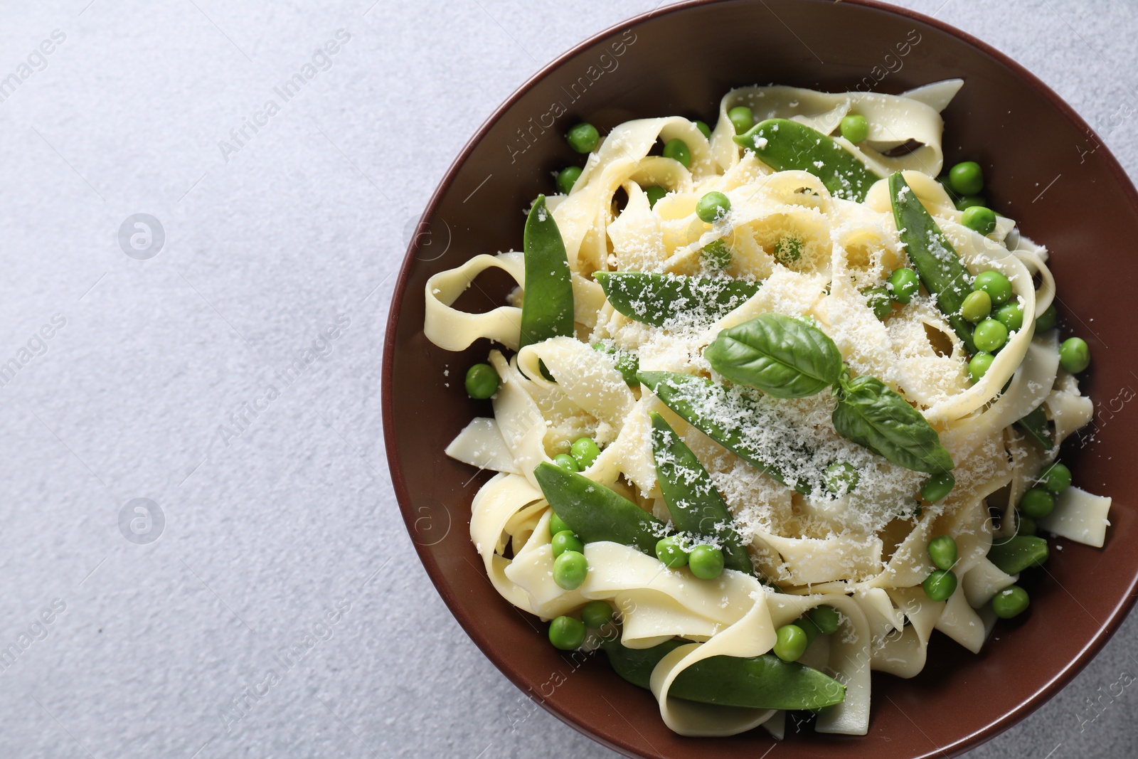 Photo of Delicious pasta with green peas and cheese on grey table, top view