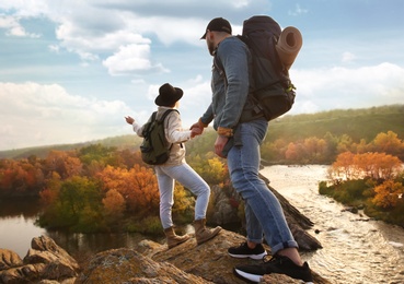 Photo of Couple of hikers with backpacks climbing up mountains