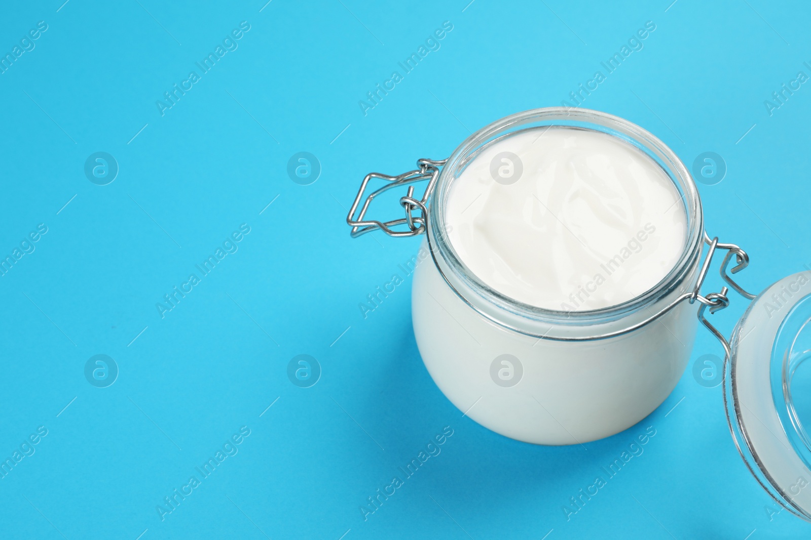 Photo of Jar of tasty organic yogurt on light blue background