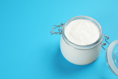 Jar of tasty organic yogurt on light blue background