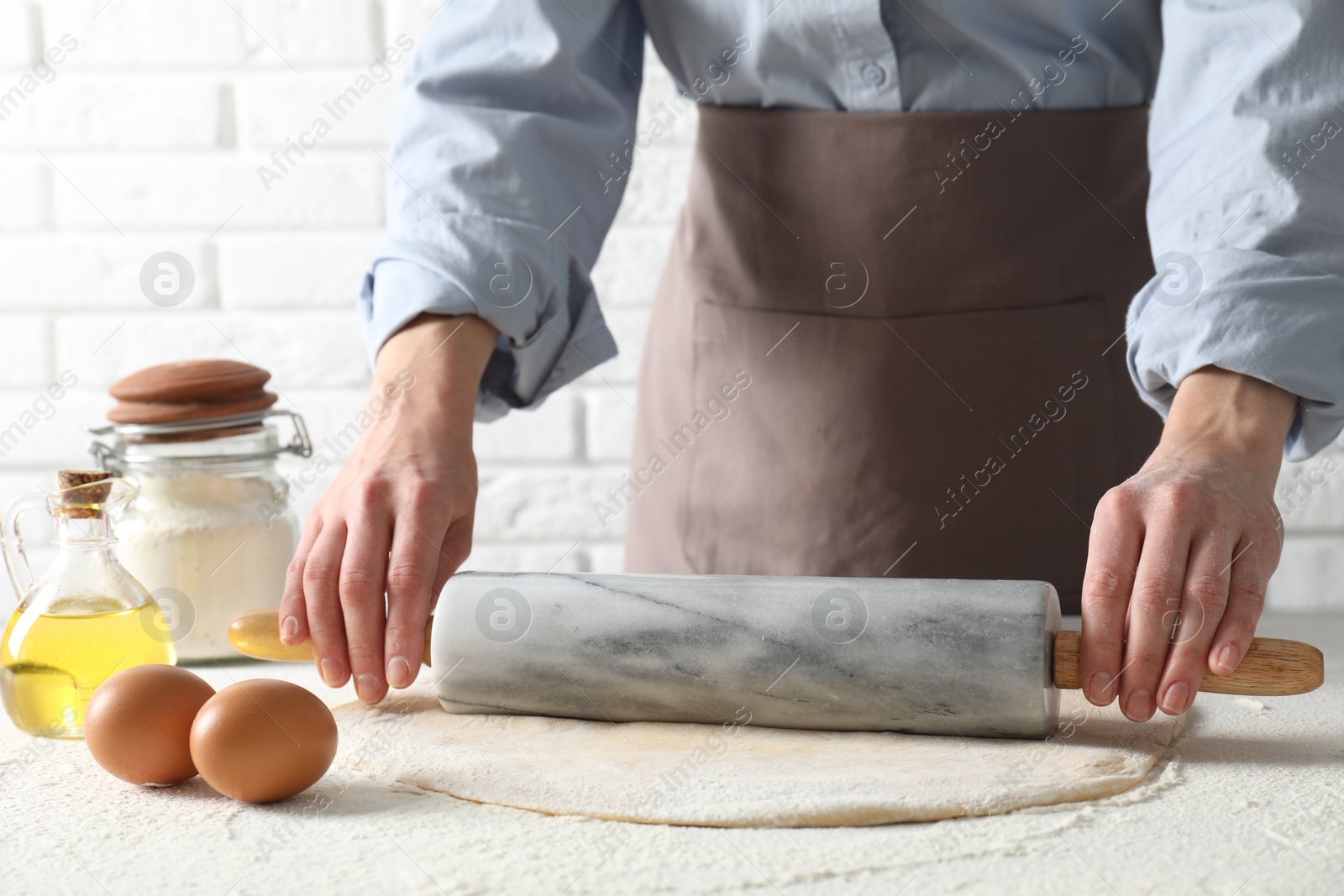 Photo of Woman rolling raw dough at table, closeup