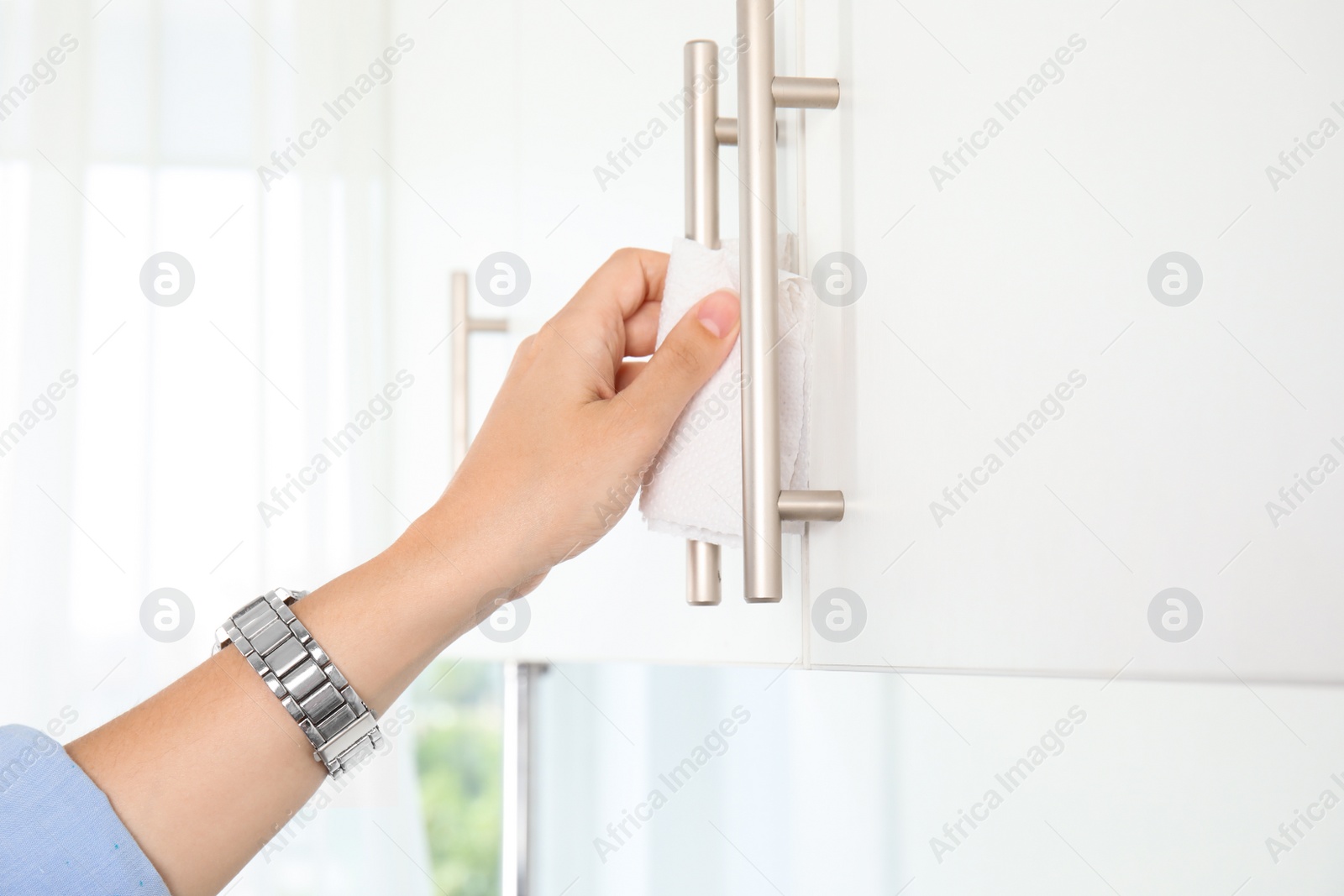 Photo of Woman using tissue paper to open cabinet door, closeup