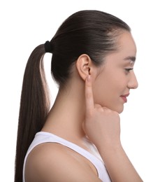 Young woman pointing at her ear on white background