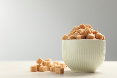 Photo of Brown sugar cubes on white table, space for text