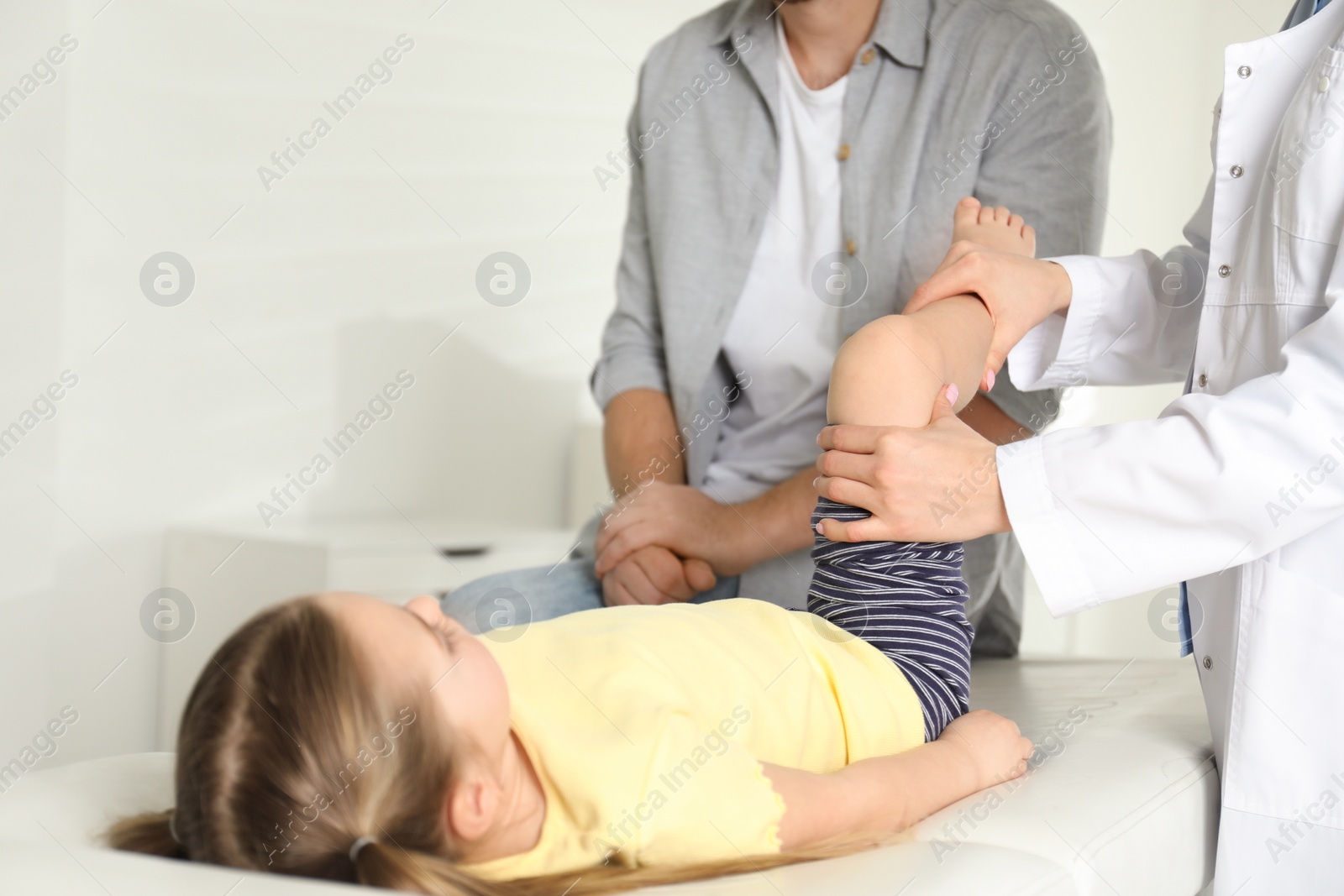 Photo of Professional orthopedist examining little patient's leg in clinic