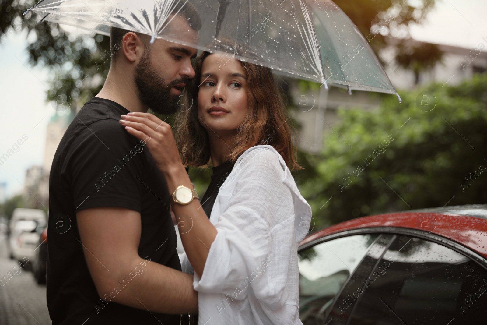 Photo of Young couple with umbrella enjoying time together under rain on city street, space for text