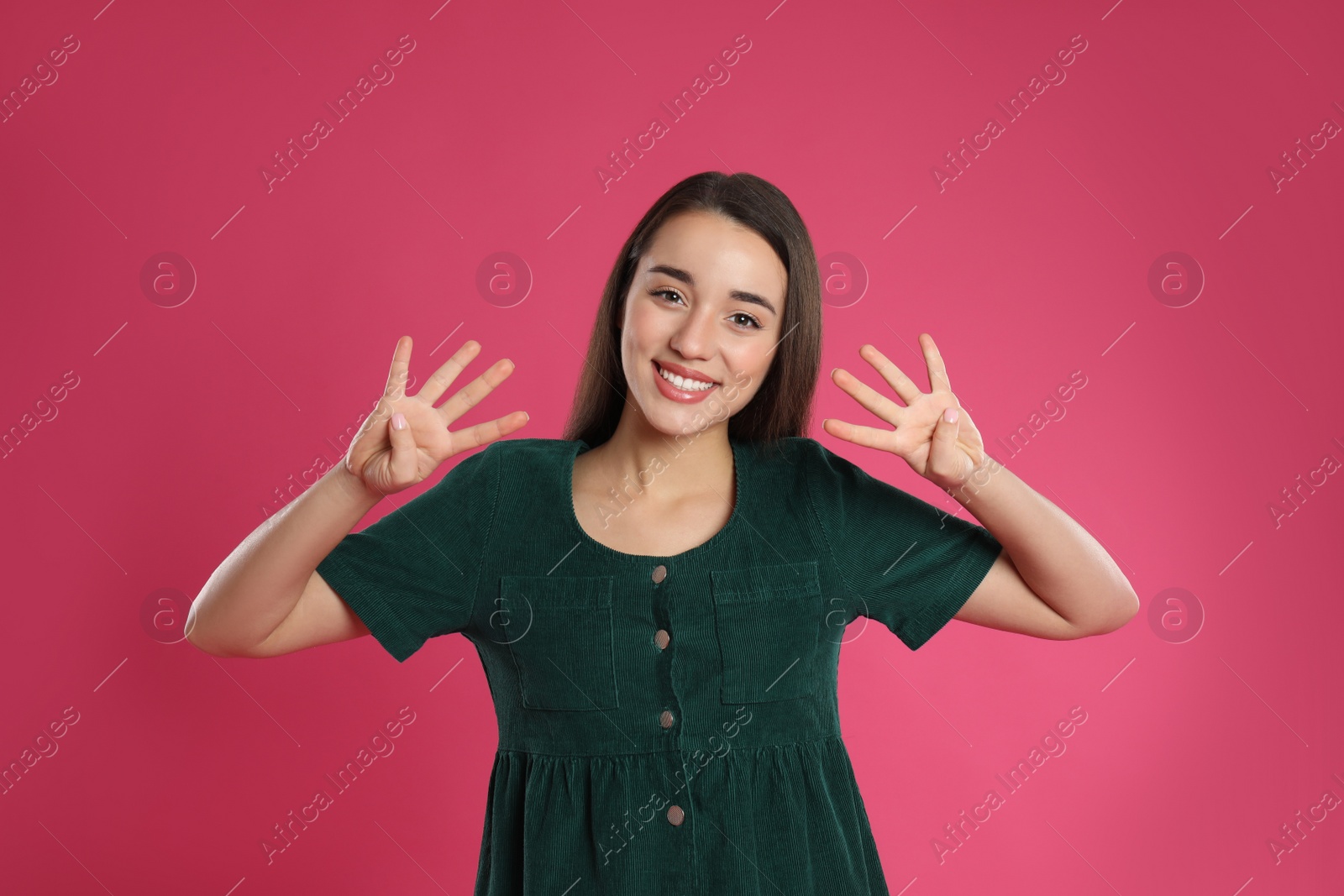 Photo of Woman showing number eight with her hands on pink background