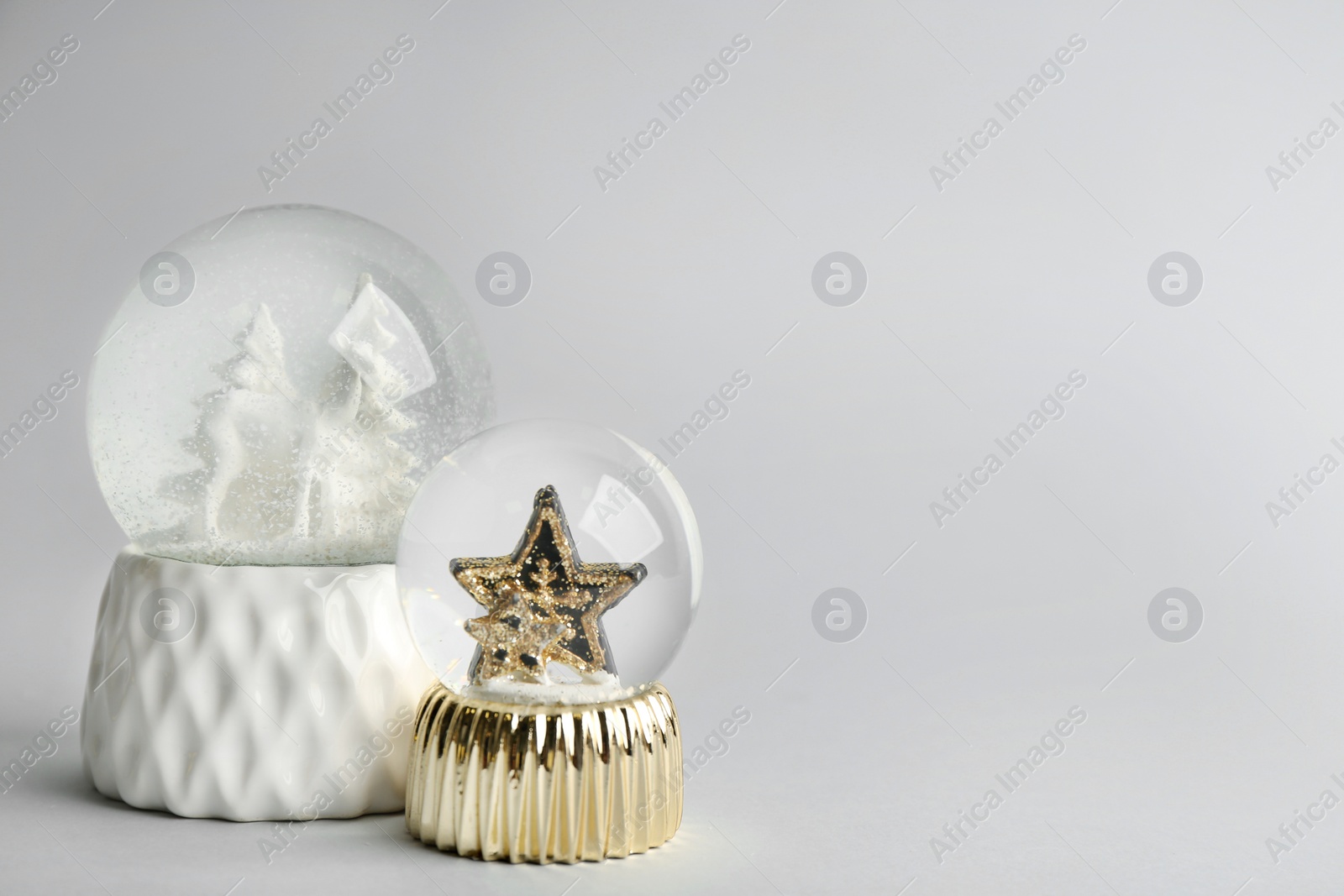 Photo of Beautiful snow globes on light grey background, space for text