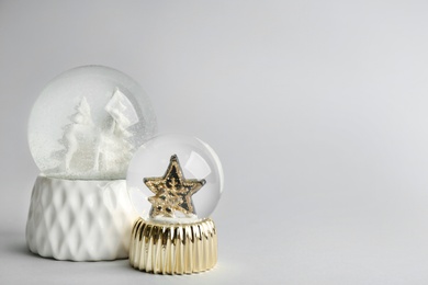 Beautiful snow globes on light grey background, space for text