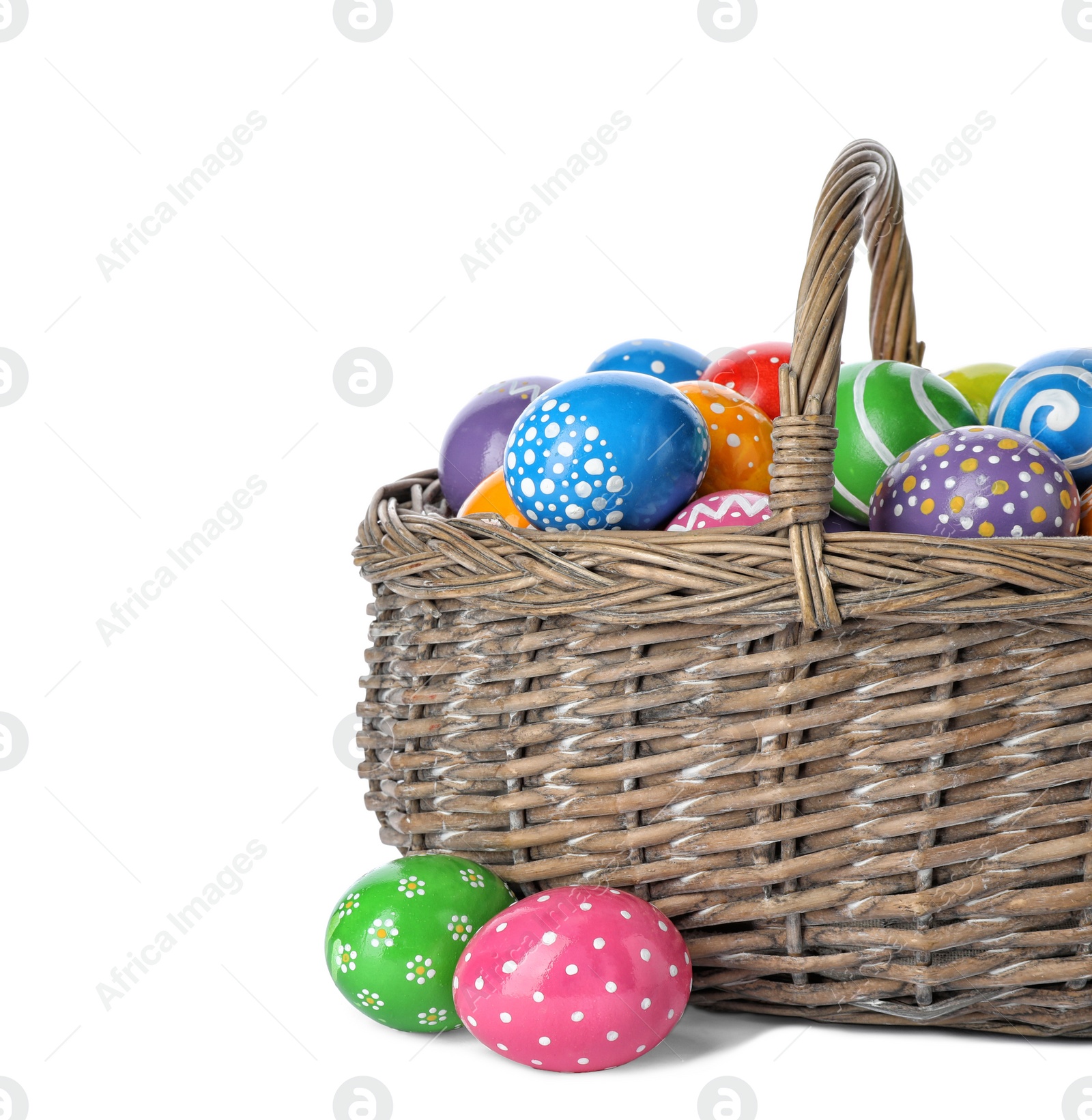 Photo of Decorated Easter eggs in wicker basket on white background