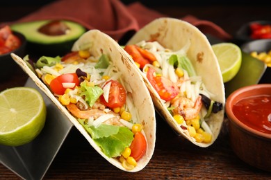 Delicious tacos with shrimps, cheese and lime on wooden table, closeup