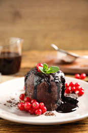 Delicious warm chocolate lava cake with mint and berries on wooden table