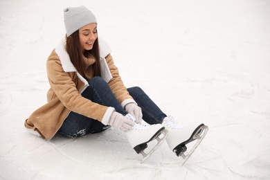 Woman lacing figure skate while sitting on ice rink