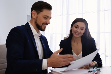 Photo of Office employees working with documents at table indoors