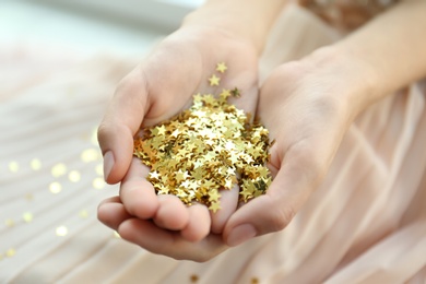 Woman holding confetti stars, closeup. Christmas celebration