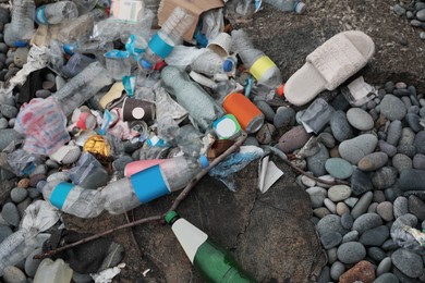 Photo of Garbage scattered on pebbles outdoors, top view. Recycling problem