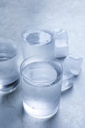Photo of Shot glasses of vodka with ice on light grey table