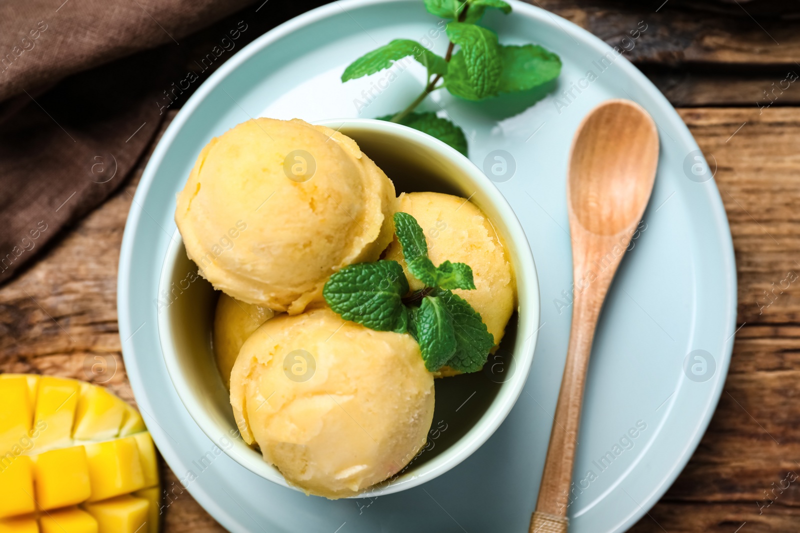 Photo of Delicious mango ice cream served on wooden table, flat lay